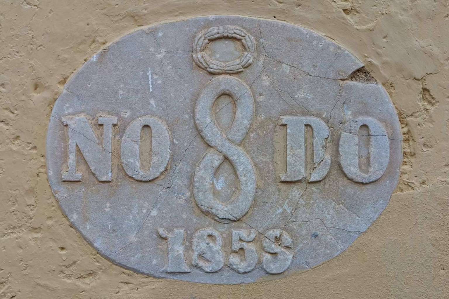 ¿Qué simboliza la inscripción situada en diferentes lugares de Sevilla, NO8DO?